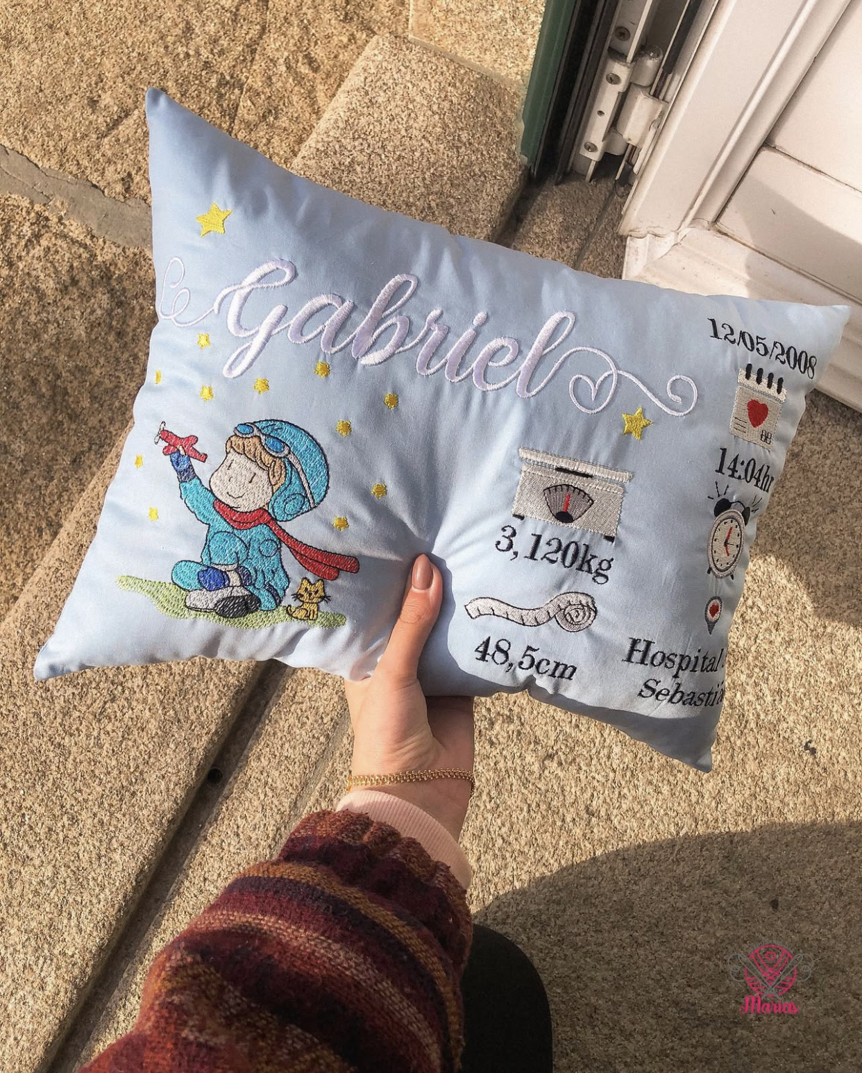Almofada azul claro com bordados de menino, estrelas e texto Gabriel e dados de nascimento