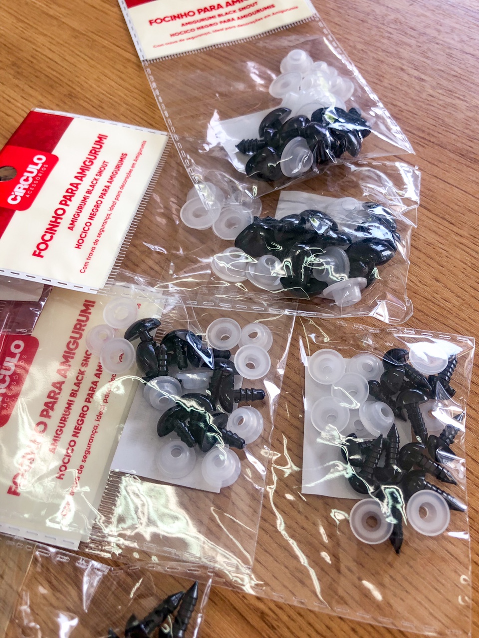 Embalagens de olhos de segurança para amigurumi sobre mesa de madeira