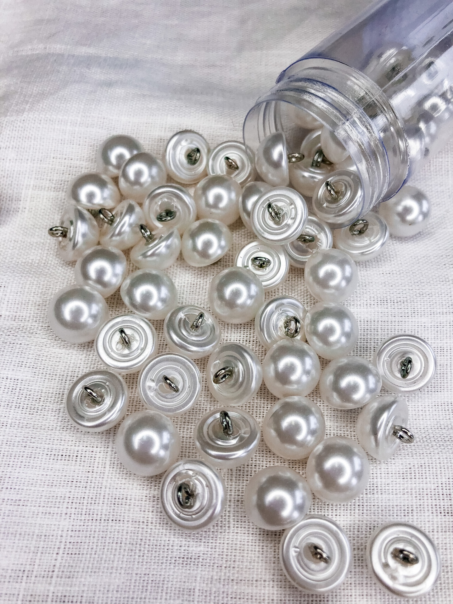 Botões de pressão pérola com metal em recipiente plástico e tecido branco