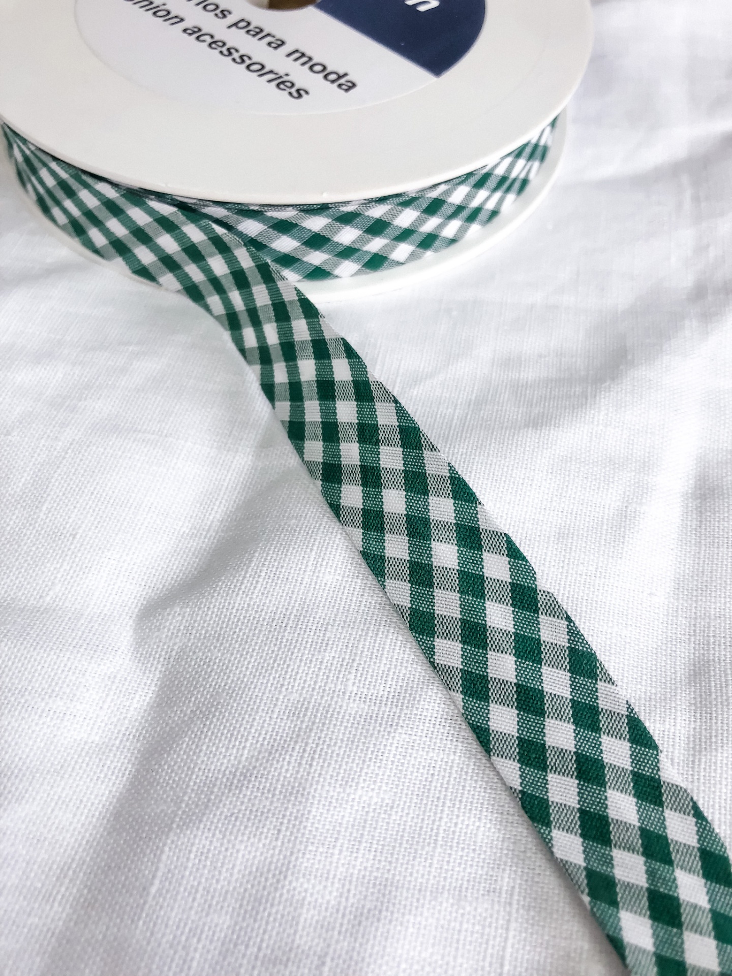 Rolo de fita xadrez verde e branco sobre tecido branco