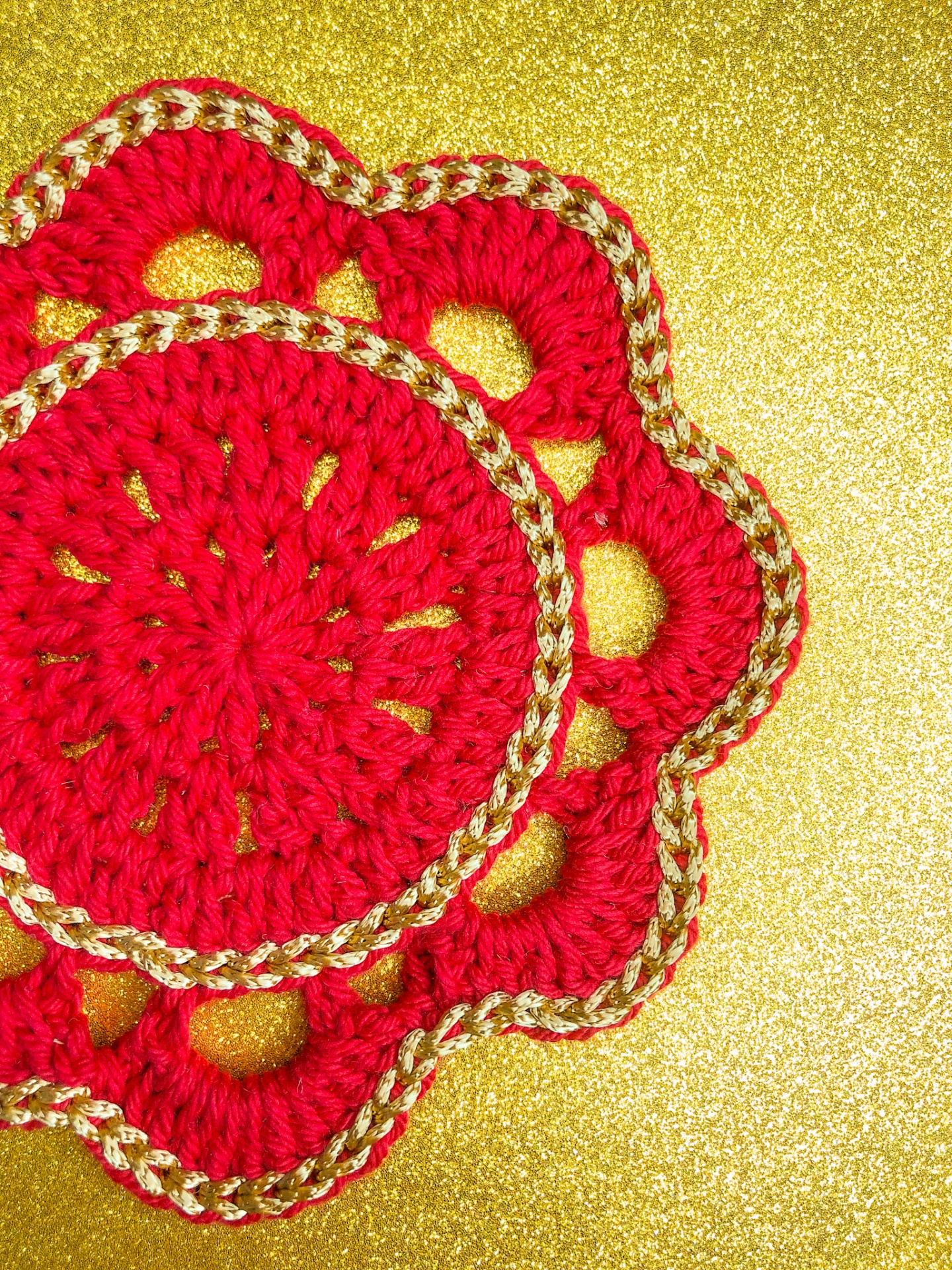 Produto artesanal em croché vermelho com detalhes dourados em fundo dourado