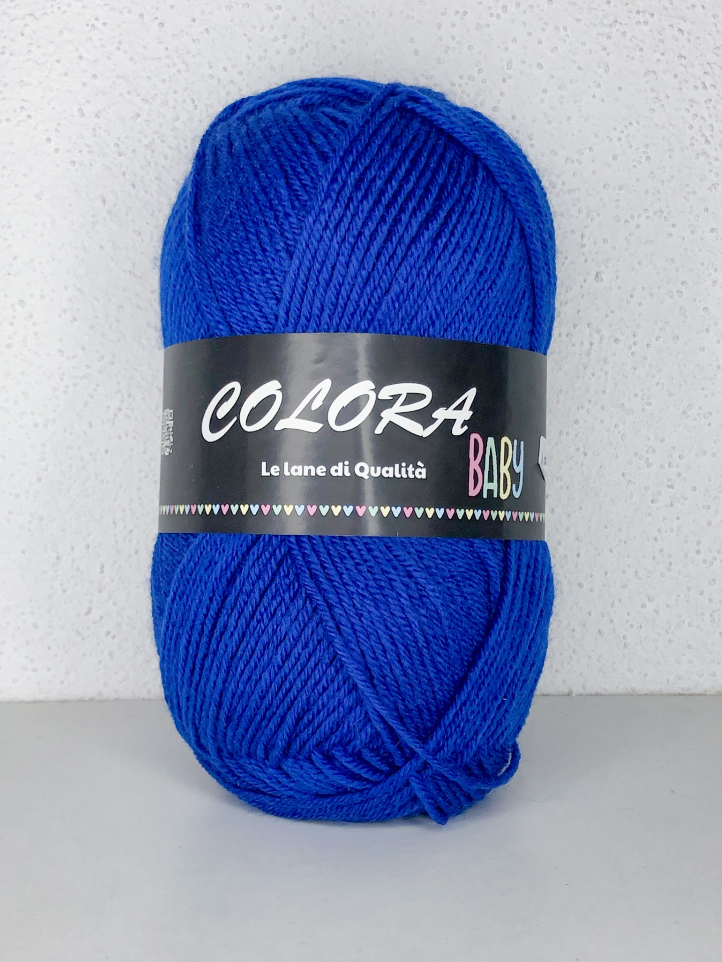 Novelo de lã azul com etiqueta preta sobre superfície branca