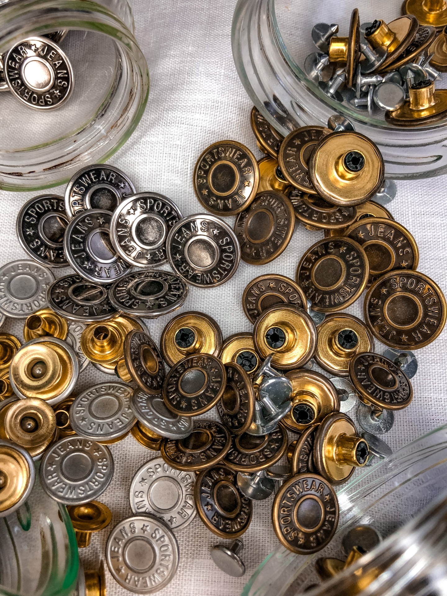 Botões metálicos coloridos e parafusos sobre superfície branca