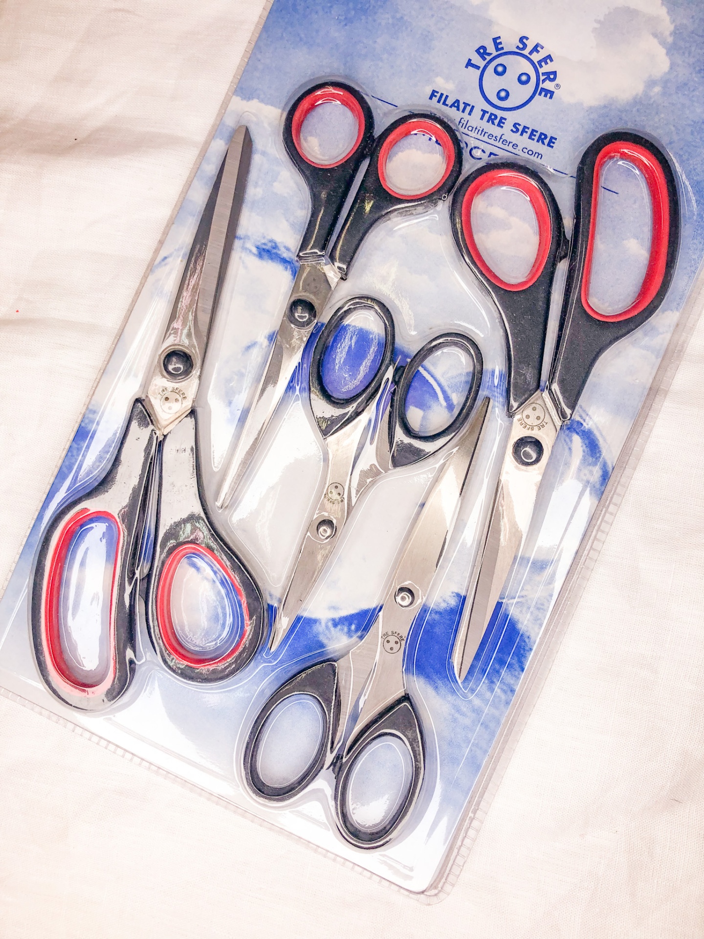 Conjunto de cinco tesouras com cabos preto e vermelho numa embalagem de plástico transparente