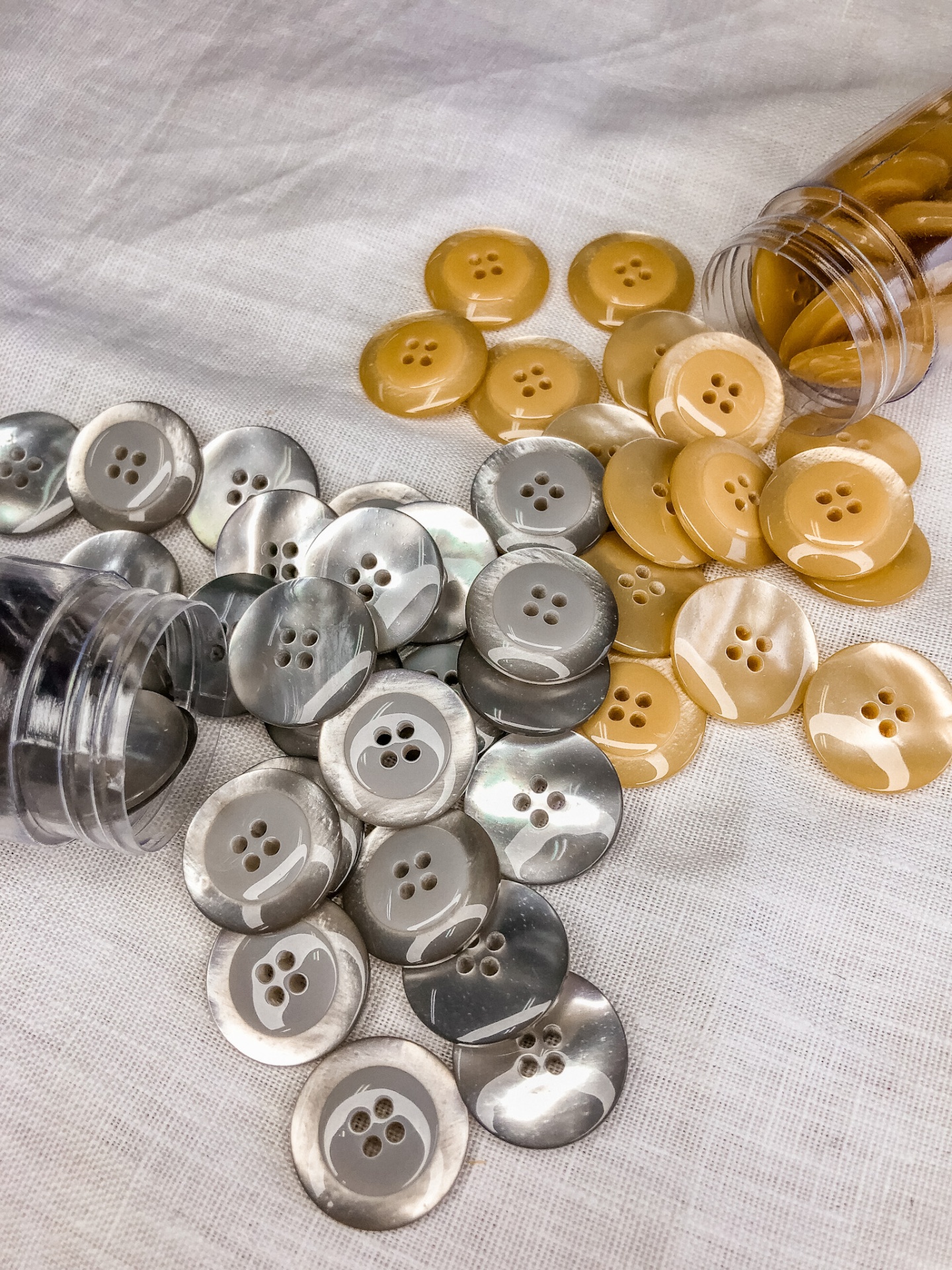 Botões redondos bege e cinza marmoreado com quatro furos em tecido branco