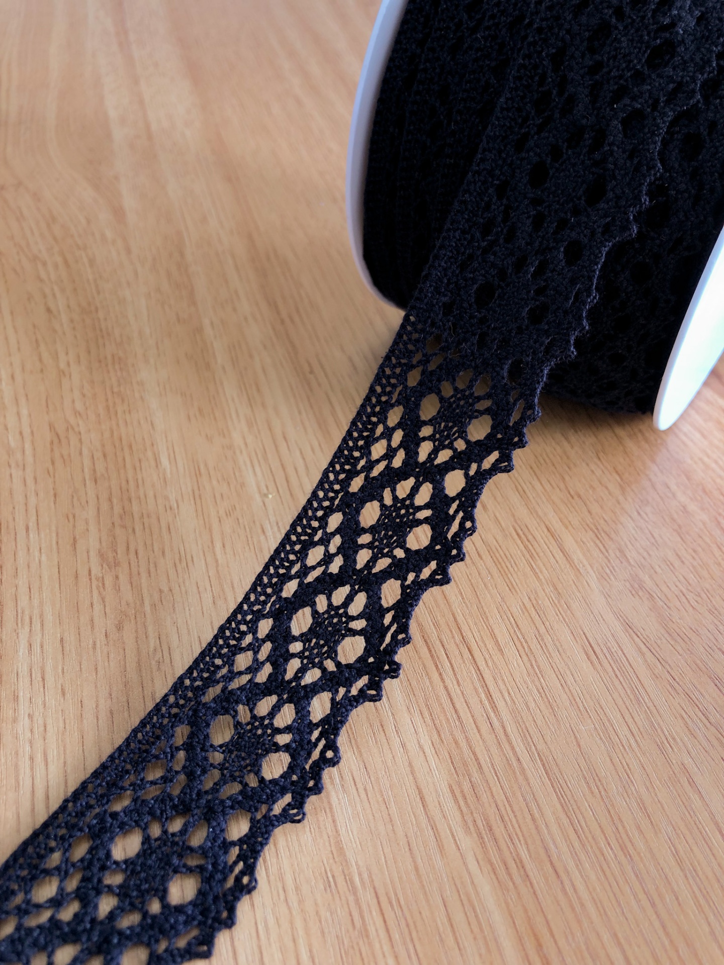 Fita de renda preta em rolo sobre superfície de madeira