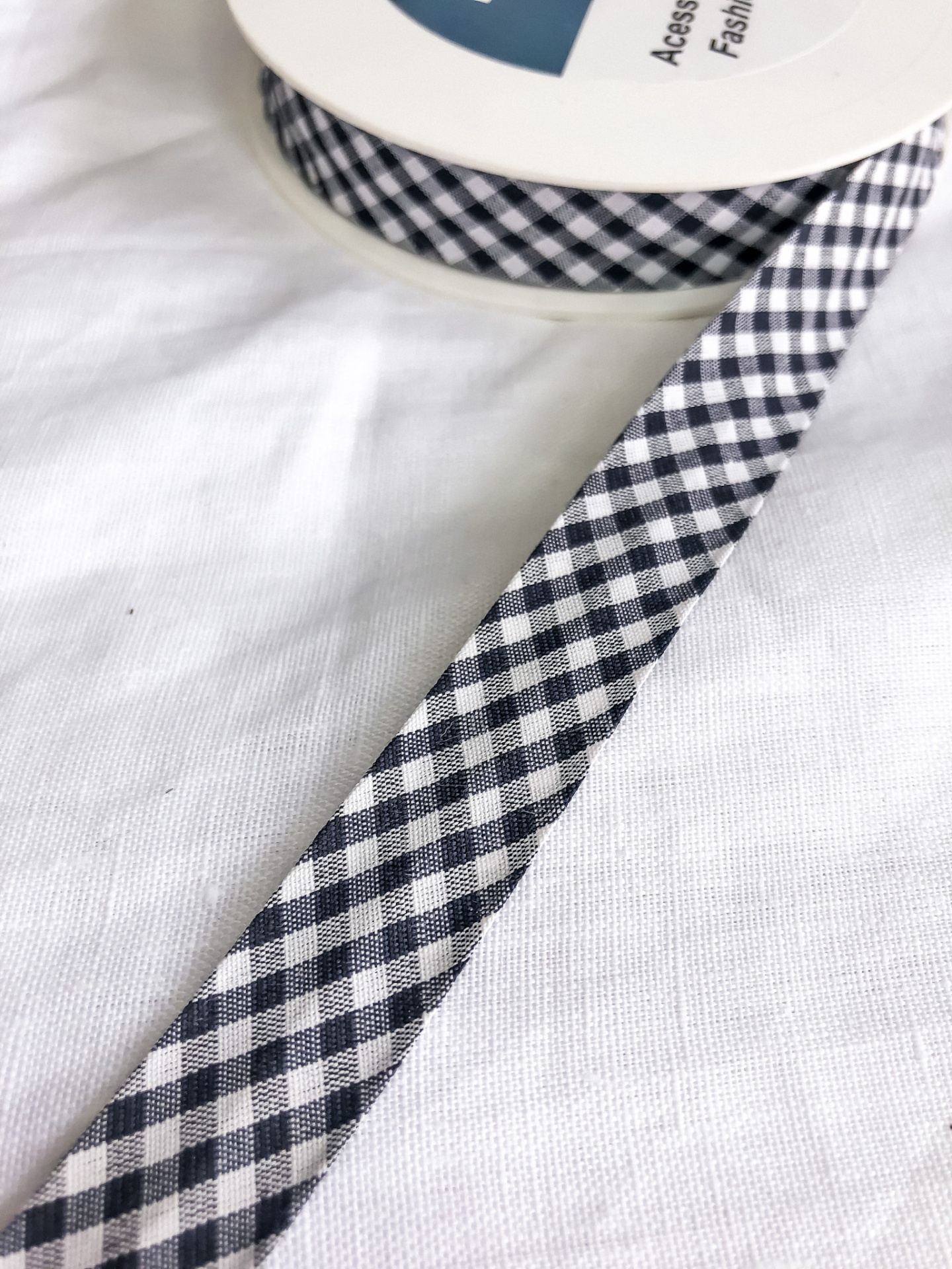 Fita xadrez preto e branco em rolo sobre tecido branco com etiqueta visível