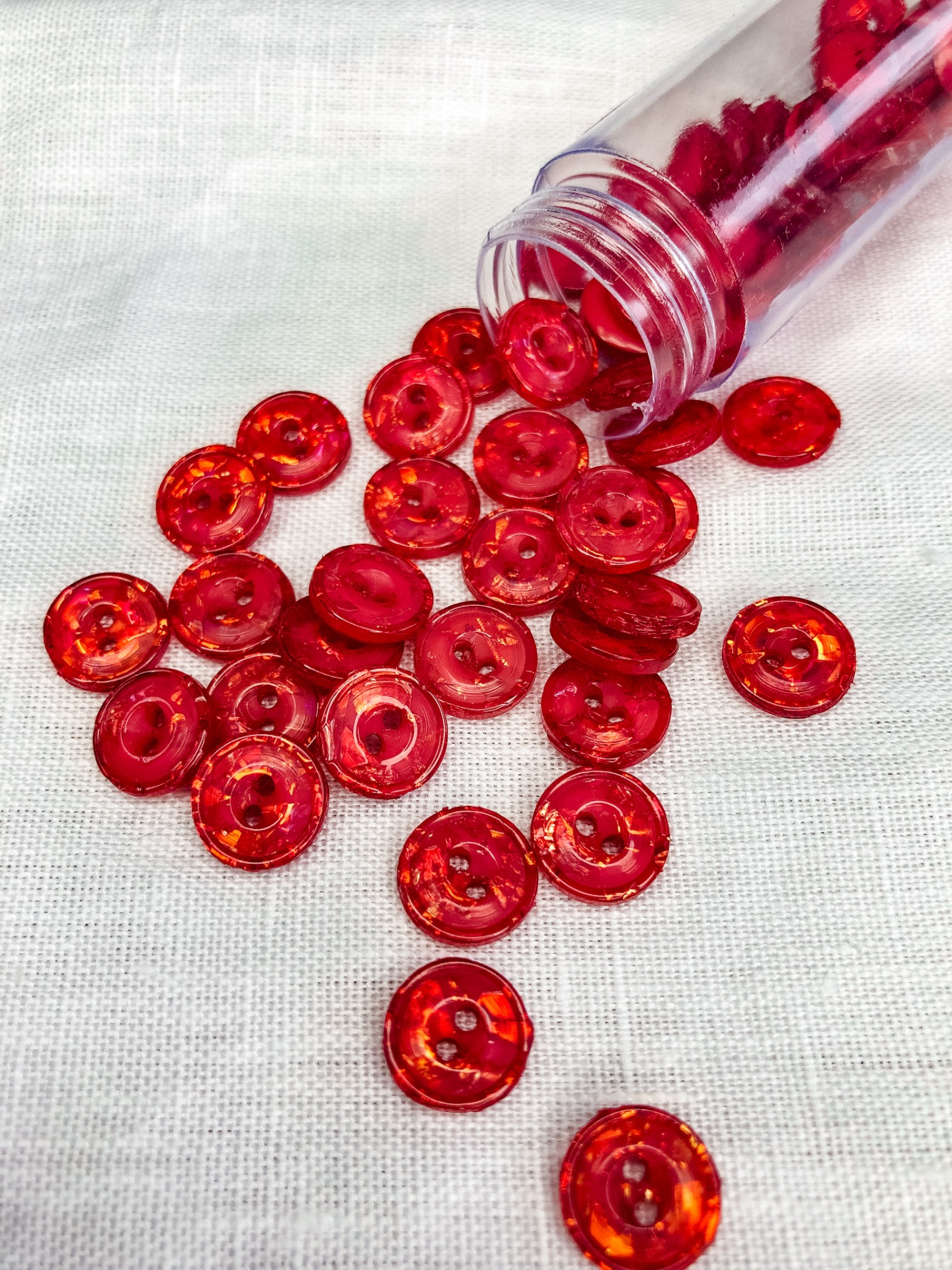 Botões vermelhos translúcidos sobre tecido branco e frasco descartado