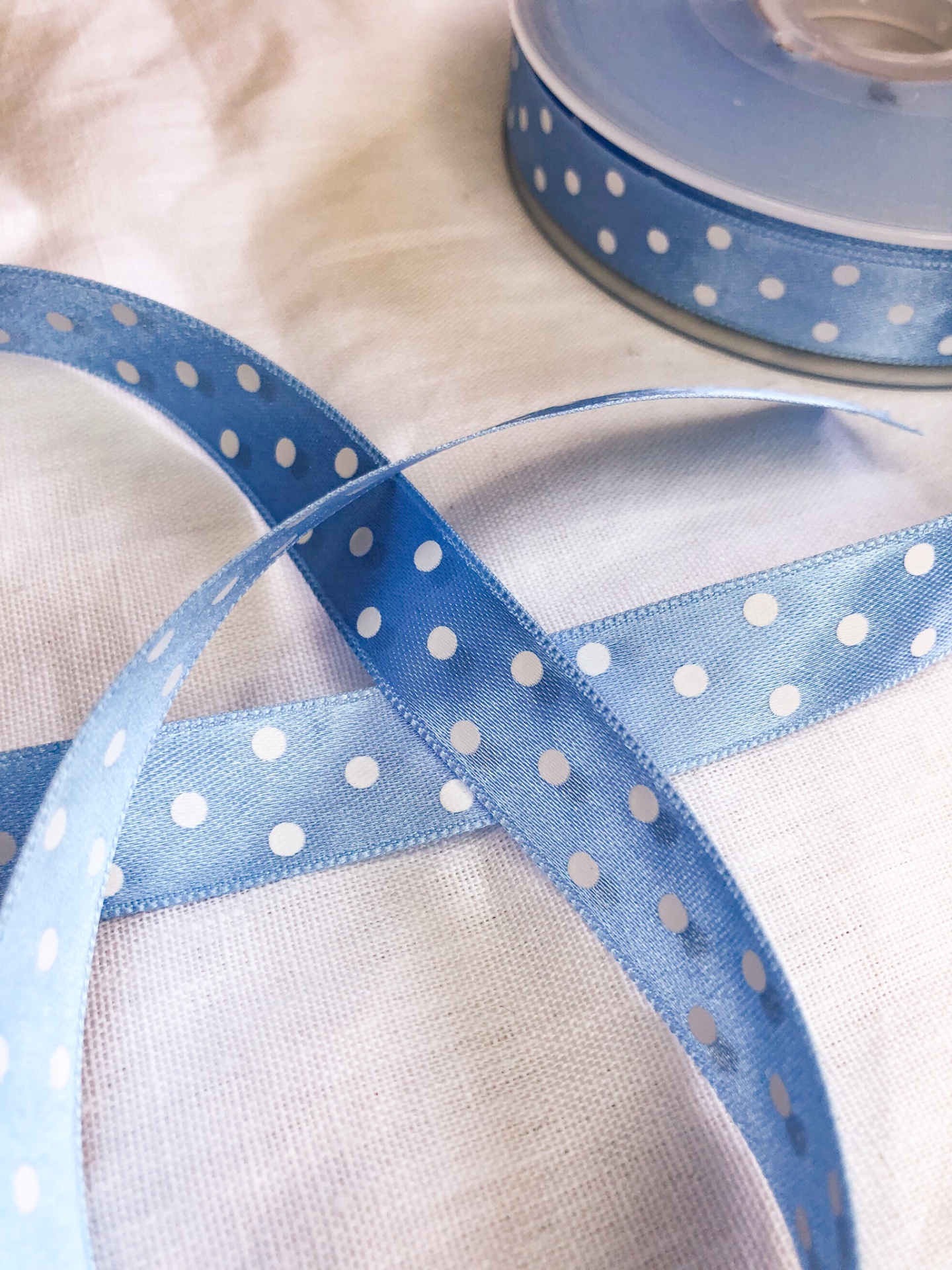 Fita azul com bolinhas brancas em tecido sobre tecido branco