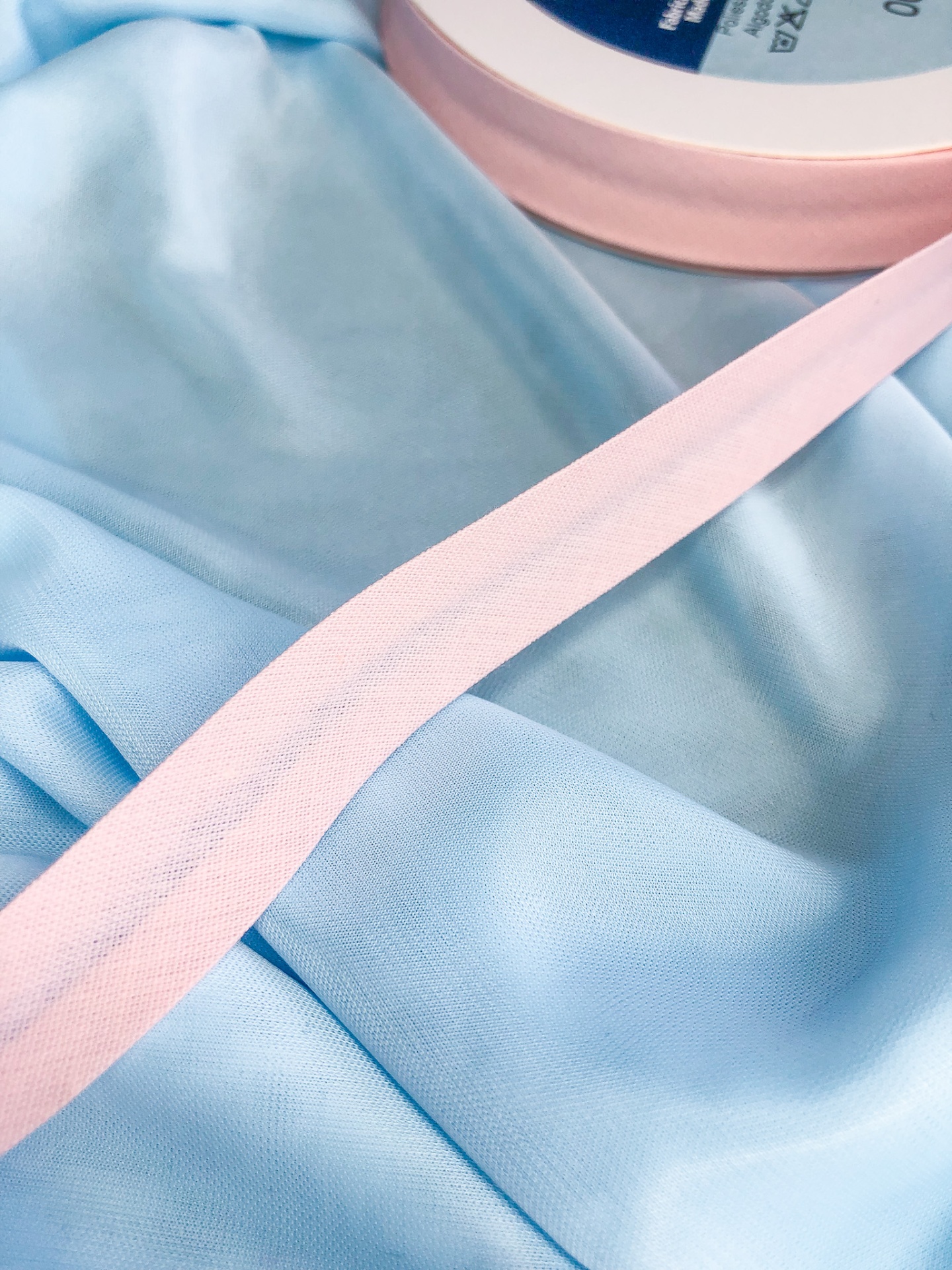 Fita de tecido cor-de-rosa num rolo sobre tecido azul claro