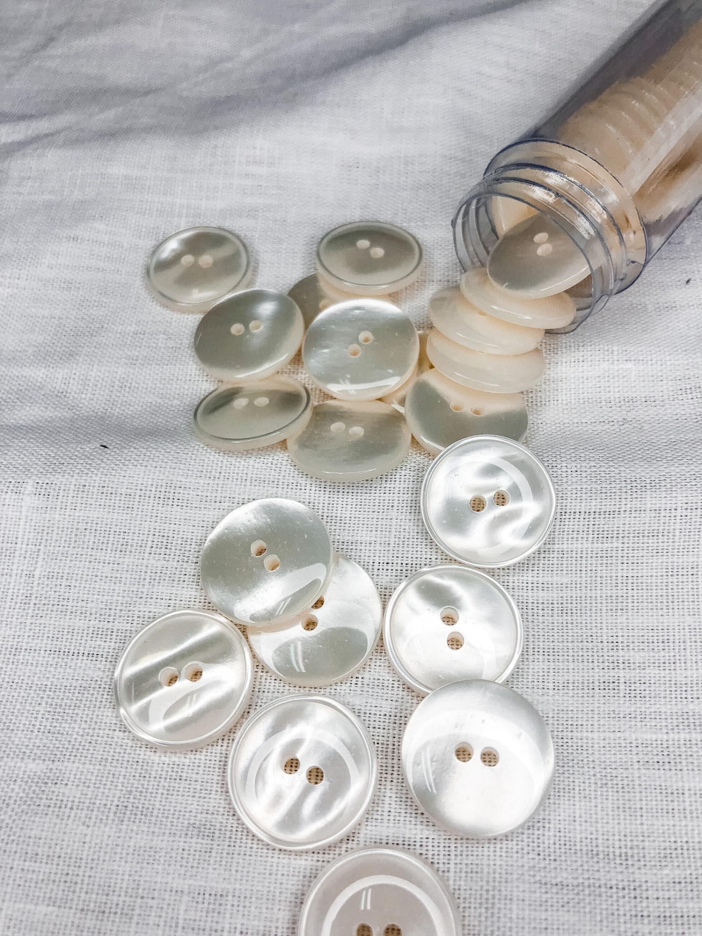 Botões redondos creme com dois buracos sobre tecido branco