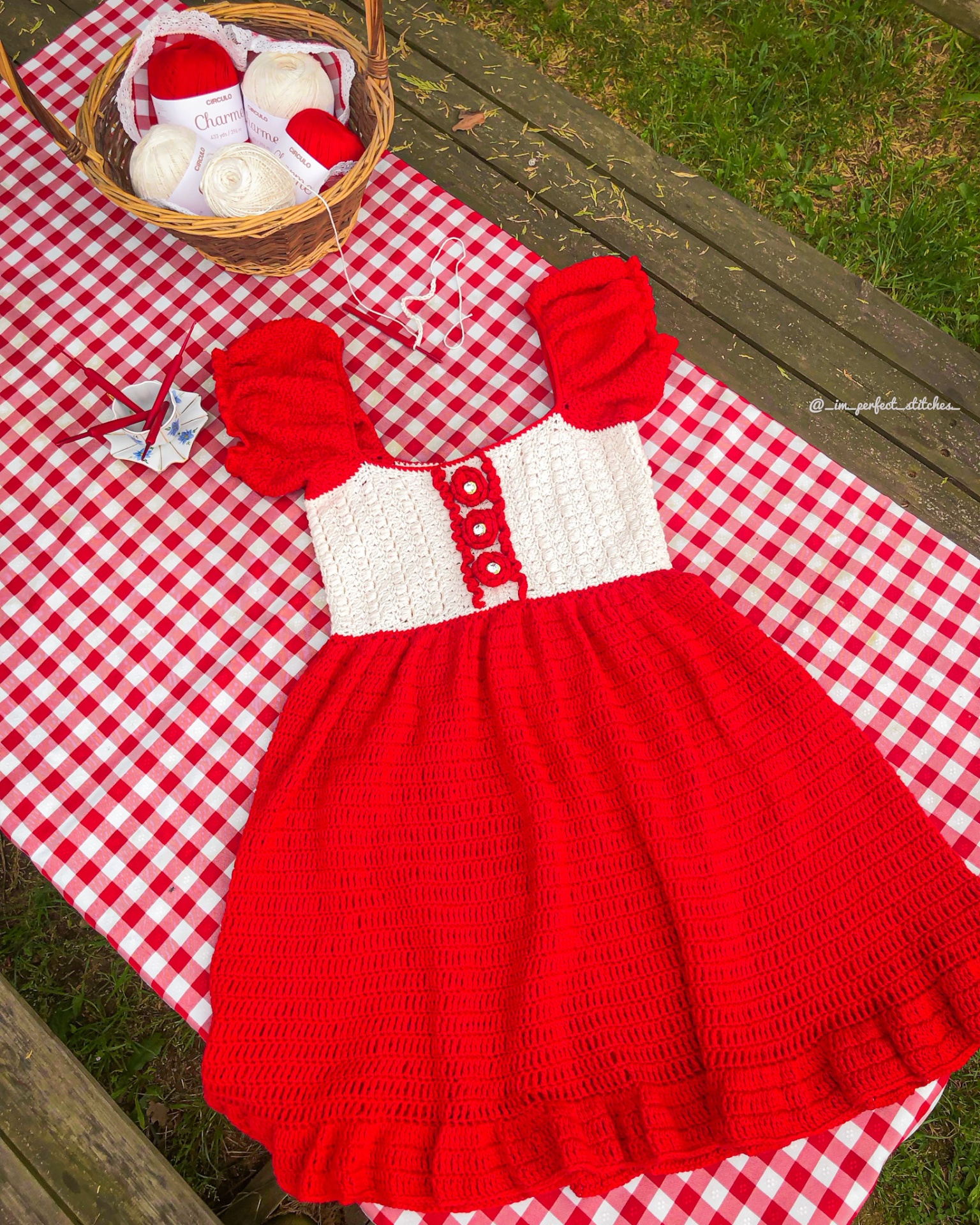 Vestido de crochet vermelho e branco sobre toalha xadrez