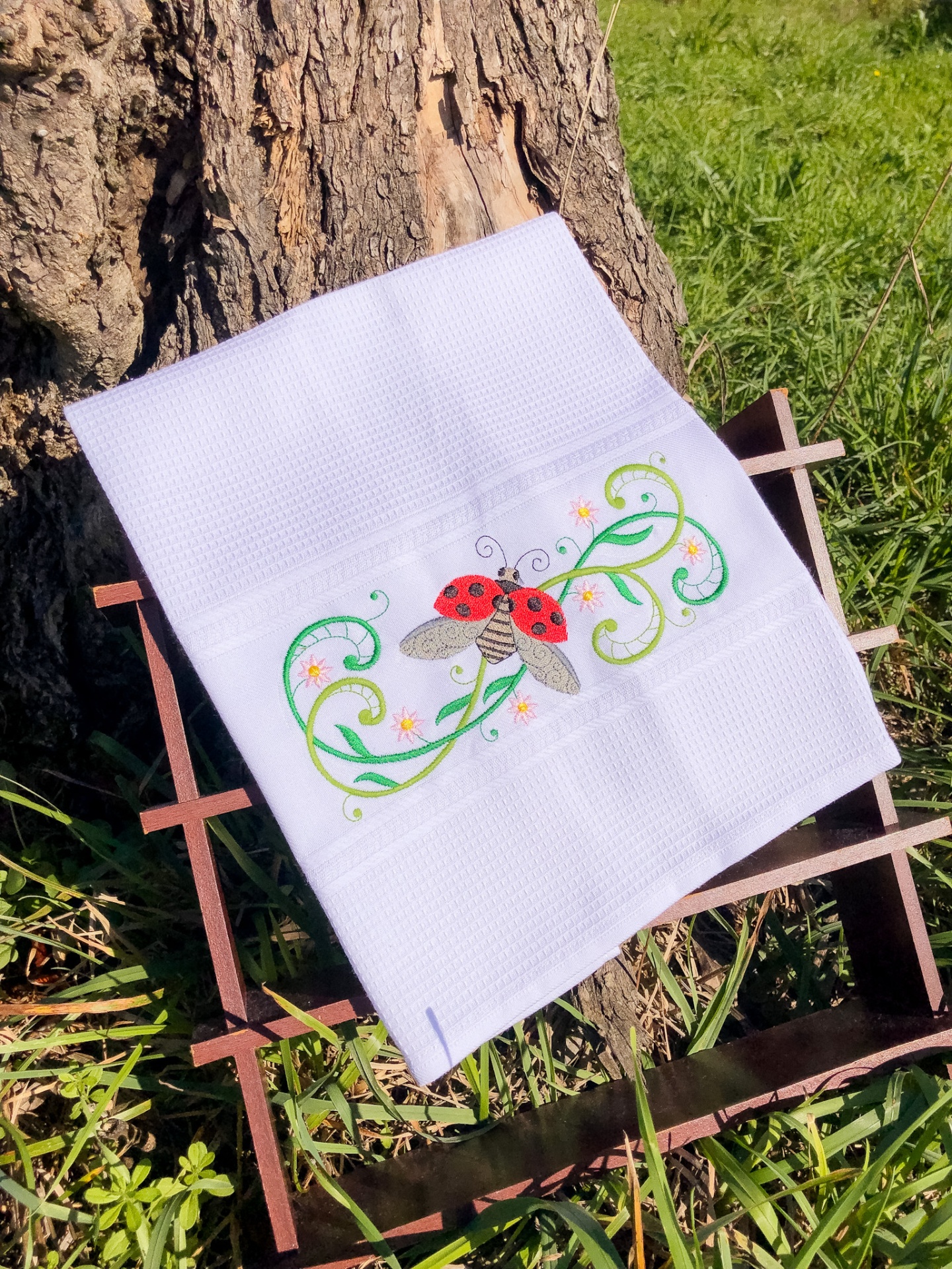 Toalha branca com bordado de joaninha e folhas verdes