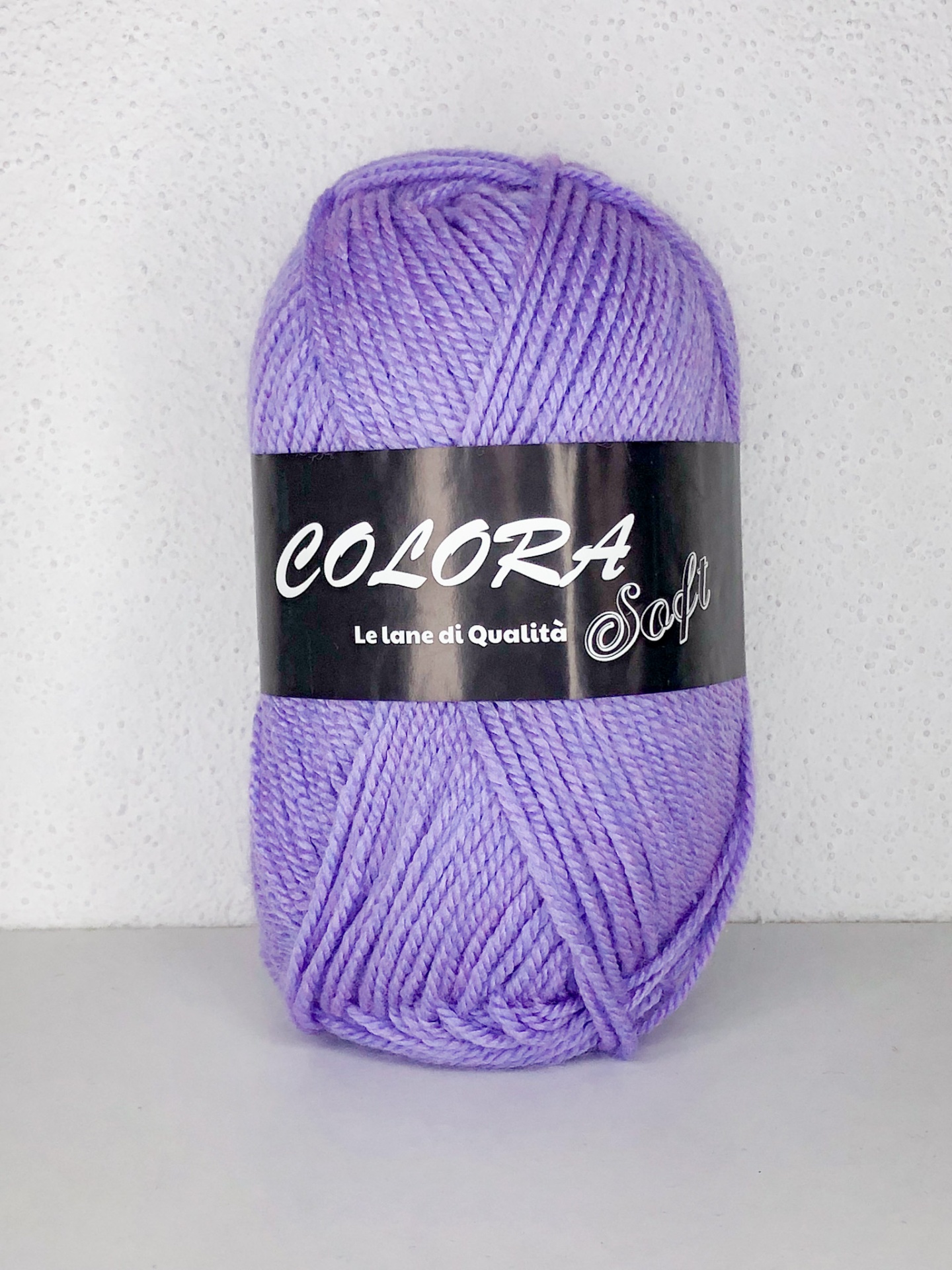 Novelo de lã lilás com rótulo preto numa superfície branca