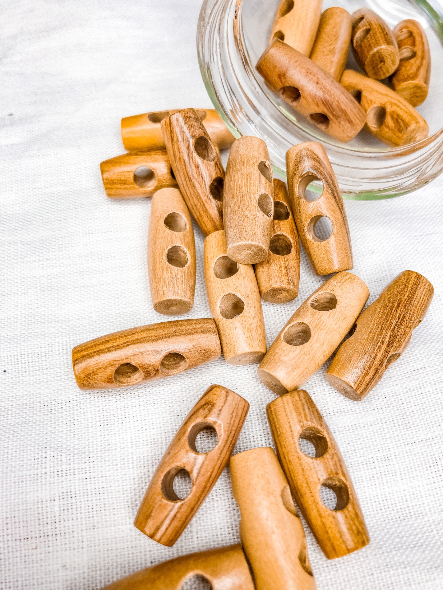 Fechos de madeira castanha com dois buracos sobre tecido branco