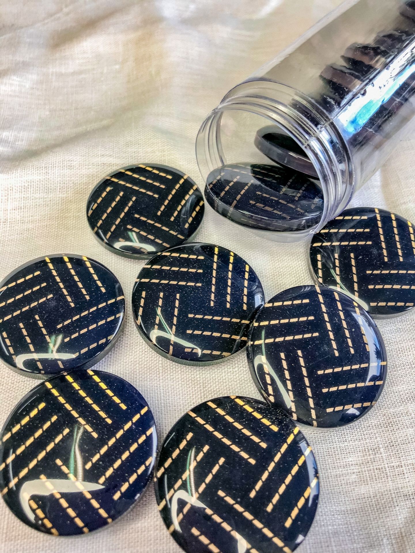 Botões redondos pretos com padrão de linhas douradas espalhados sobre superfície branca