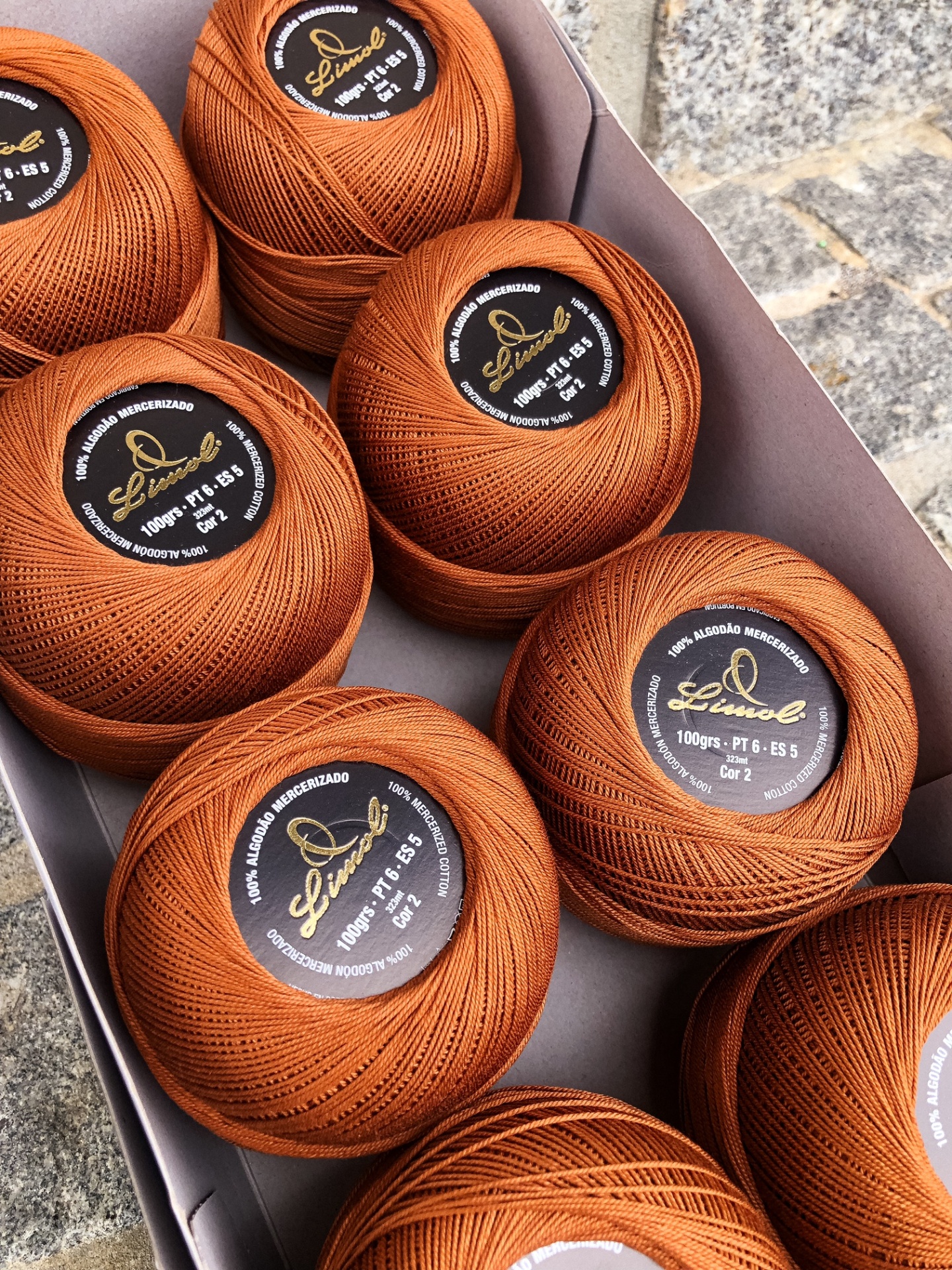 Bolas de linha de algodão mercerizado castanho alaranjado numa caixa