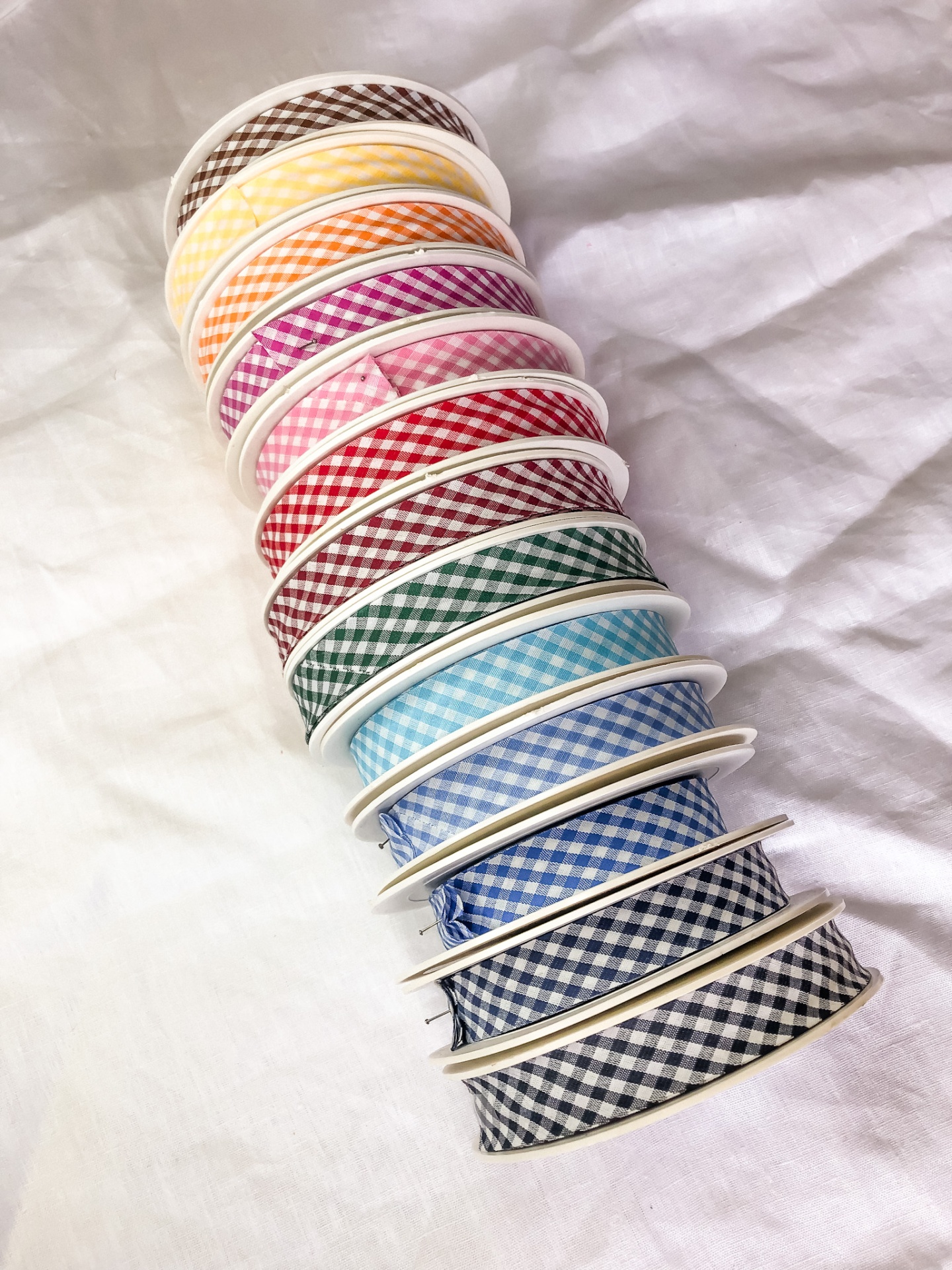 Rolos de fita decorativa xadrez em várias cores sobre tecido branco