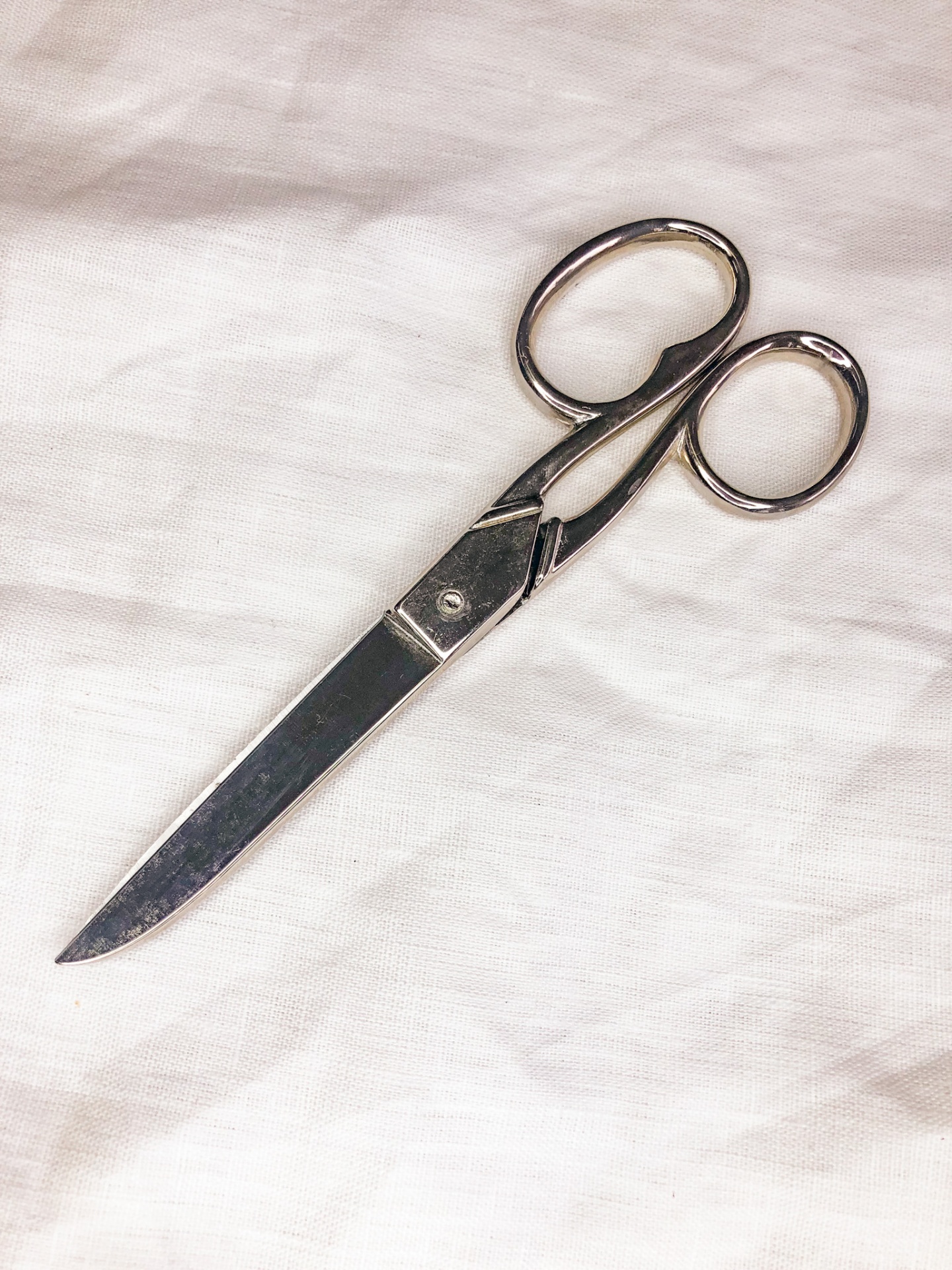 Tesoura metálica prateada sobre tecido branco