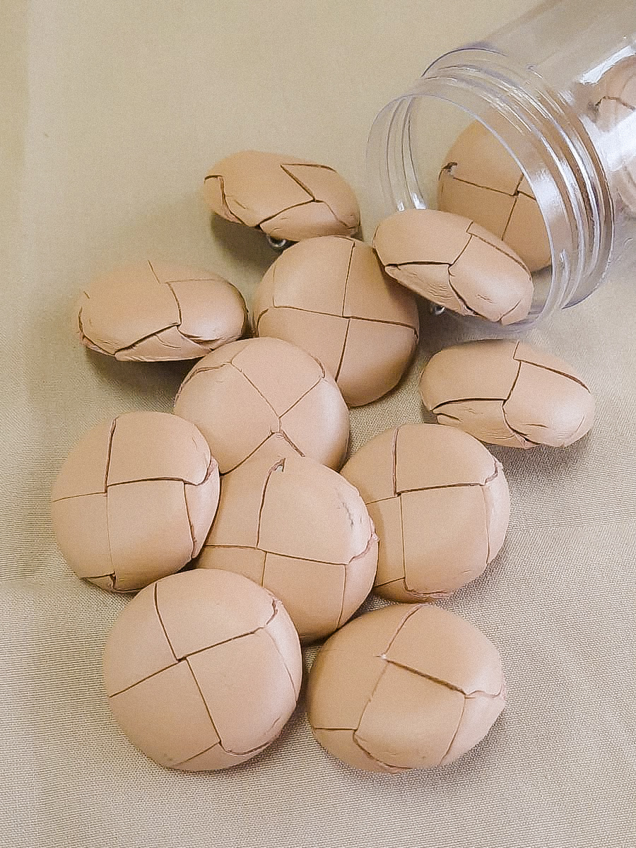 Pincéis de maquilhagem cor de pele com marcas de cortes triplos perto de frasco de vidro