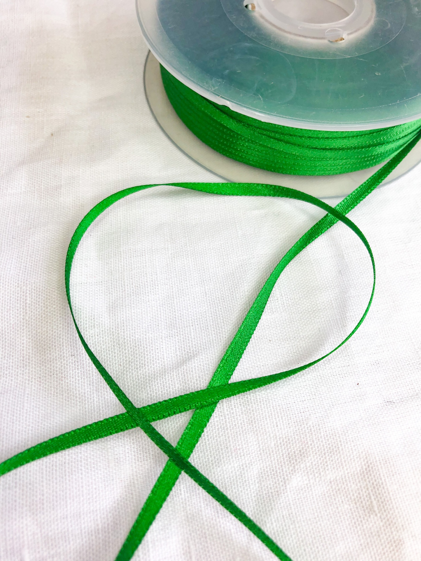 Rolo de fita verde sobre tecido branco