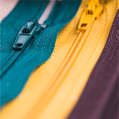 Três fechos éclair de cores verde, amarelo e castanho em tecido