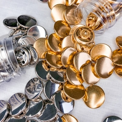 Botões metálicos redondos dourados e prateados sobre fundo branco