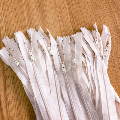Muitos fechos éclair brancos lado a lado sobre uma superfície de madeira.