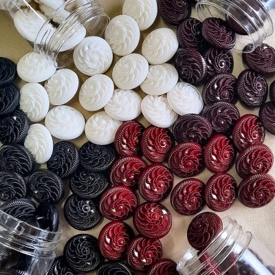 Botões redondos coloridos com padrão espiral em recipientes transparentes sobre superfície clara