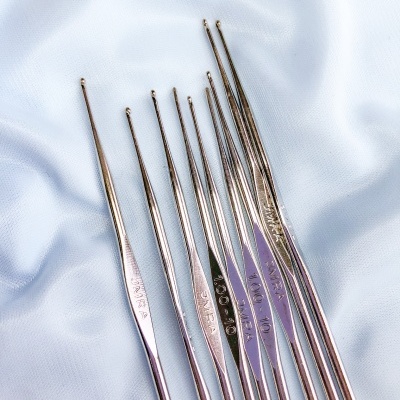 Conjunto de agulhas de croché metálicas prateadas em tecido azul claro