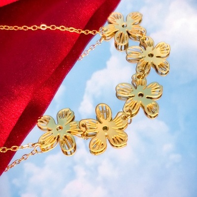 Colar dourado com cinco flores decorativas sobre fundo vermelho e céu azul