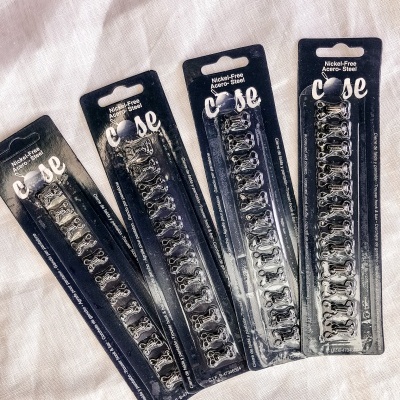 Pacotes de ganchos metálicos em fundo azul escuro sobre tecido branco