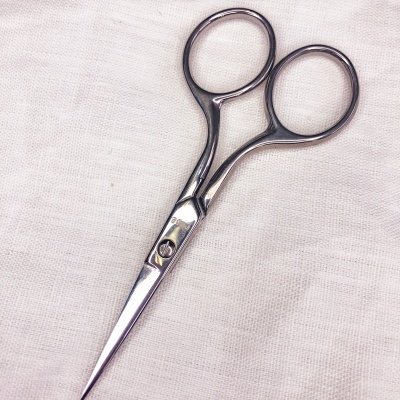 Tesoura pequena prateada sobre tecido branco