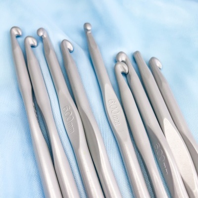 Agulhas de crochet prateadas com tamanhos gravados sobre tecido azul