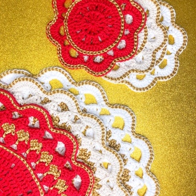 Apliques e marcador de copo em crochet vermelho, branco e dourado sobre fundo dourado