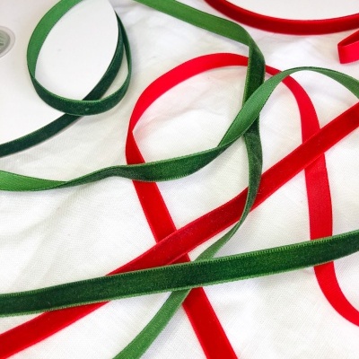 Fitas de veludo verde e vermelho com carretéis sobre pano branco