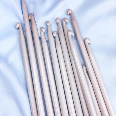 Agulhas de tricô de madeira clara em vários tamanhos sobre tecido azul claro