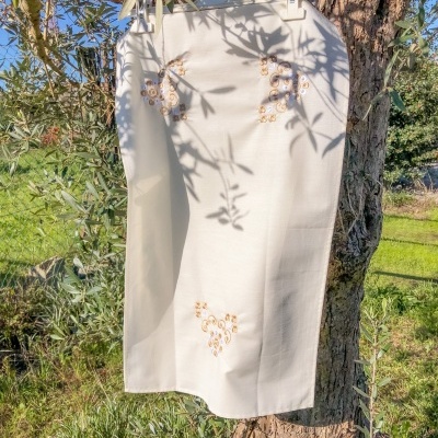 Saia branca bordada pendurada em árvore ao ar livre