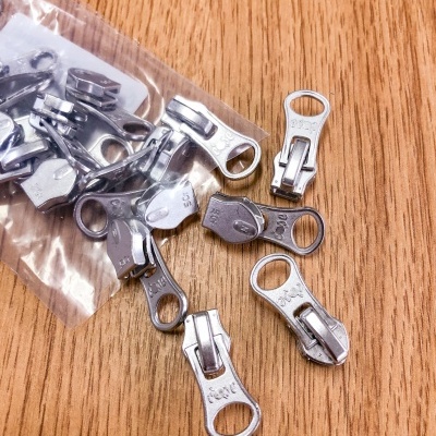 cursores metálicos de fecho éclair prateados numa mesa de madeira