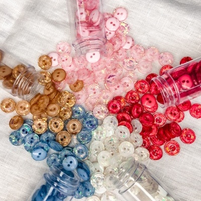 Botões coloridos pequenos espalhados com embalagens cilíndricas transparentes