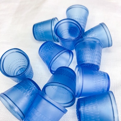 Onze copos pequenos azuis de plástico com textura quadriculada sobre pano branco