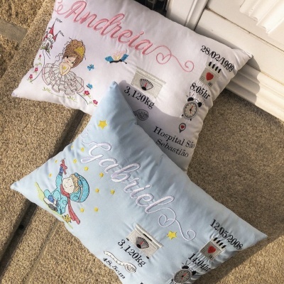 Duas almofadas personalizadas em branco e azul claro com nomes e detalhes bordados