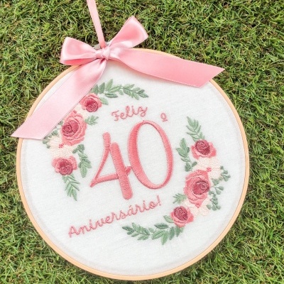 Aro de bordado com texto e decoração floral sobre relva
