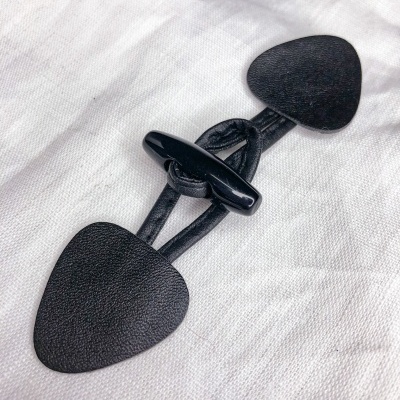 Fecho de casaco preto em couro texturado sobre tecido branco