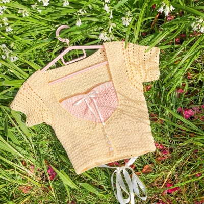 Camisola de malha bege em cabide sobre relva com flores