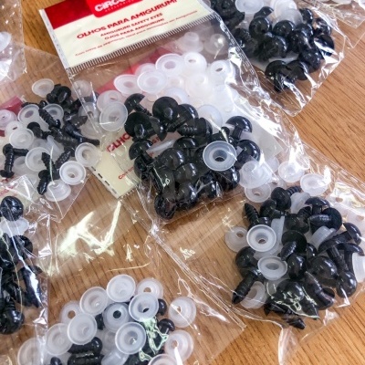 Pacotes de olhos de plástico para amigurumi Circulo em sacos transparentes sobre mesa de madeira