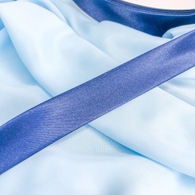 Rolo de fita de cetim azul escuro sobre tecido azul claro