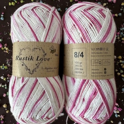 Duas meadas de fio de algodão branco e rosa com etiquetas Rustik Love e informações de peso e composição