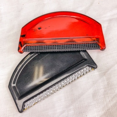 Dois raspadores para gelo, vermelho e preto, sobre tecido claro