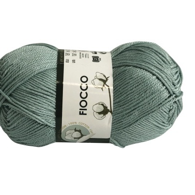 Novelo de fio de algodão verde azulado com etiqueta branca com texto e desenhos